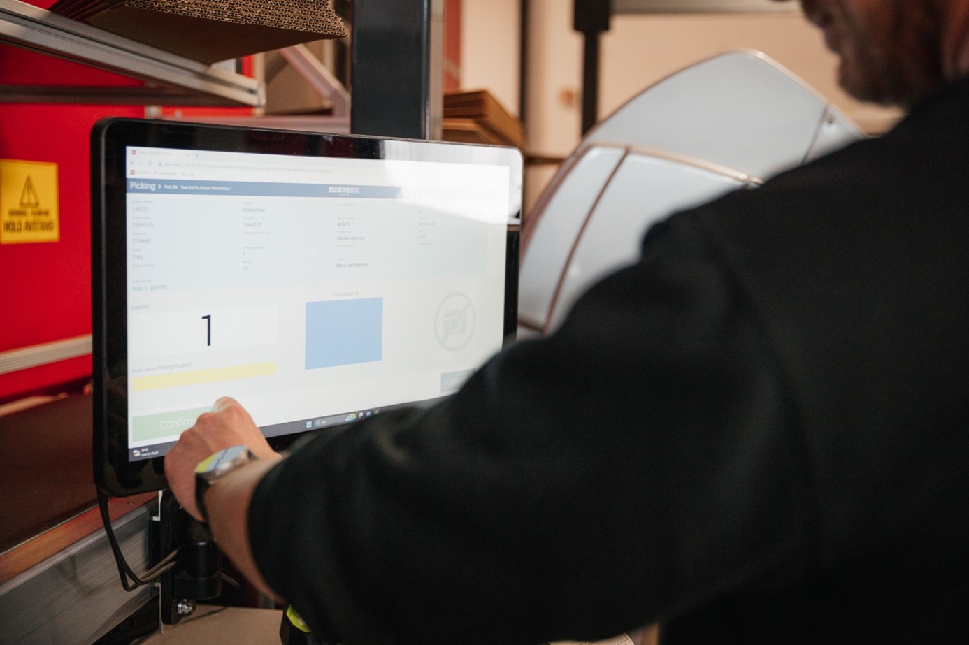Muž používá dotykovou obrazovku k dokončení objednávek v systému AutoStore.